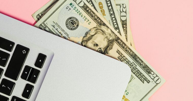 Laptop on a pink background with cash underneath