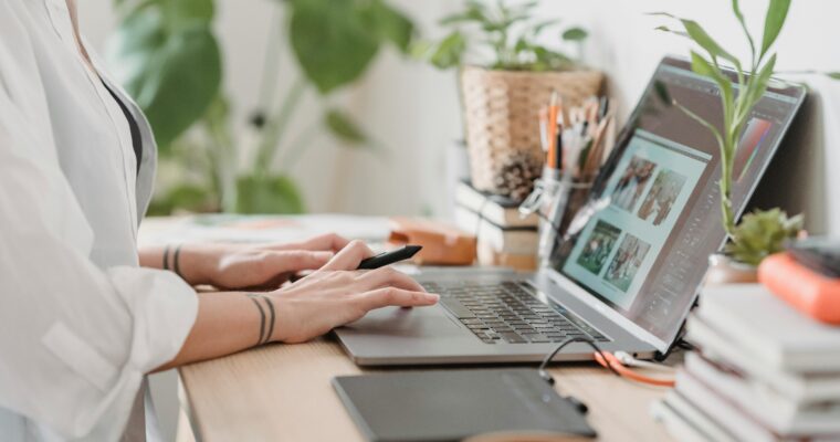 Woman working at desk retouching a photo on a laptop at home.